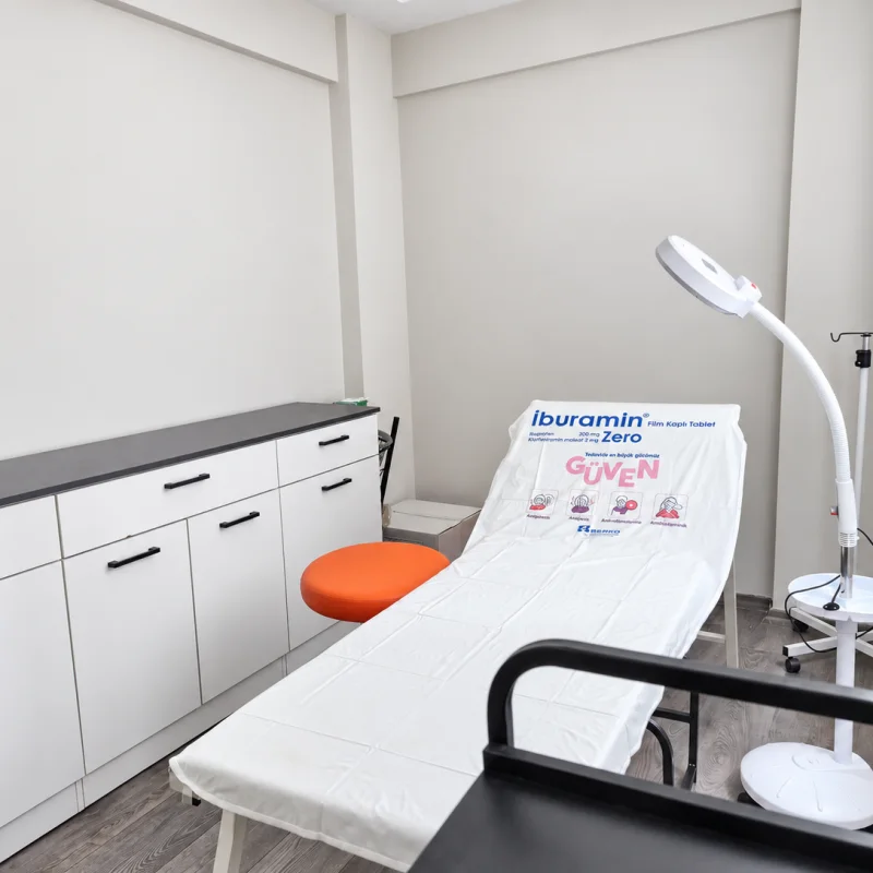 Kliniğin hazırlık alanı: dolaplar, muayene masası ve büyüteçli lamba